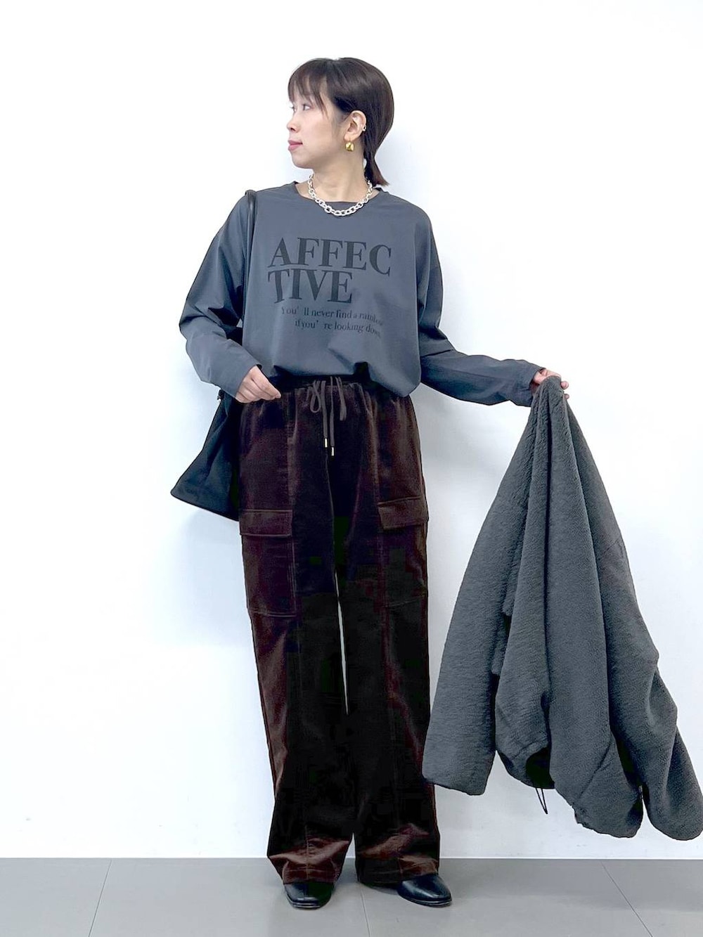 ブラック系のブーツ、グレー系のブルゾン、シルバー系のネックレスを着用したレディースの秋コーディネートの8枚目の写真