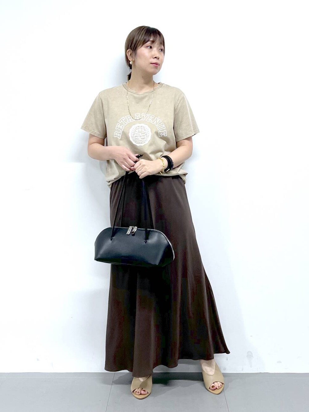 ブラック系のトートバッグ、ベージュ系のサンダル、ベージュ系のTシャツ/カットソーを着用したレディースの夏コーディネートの4枚目の写真