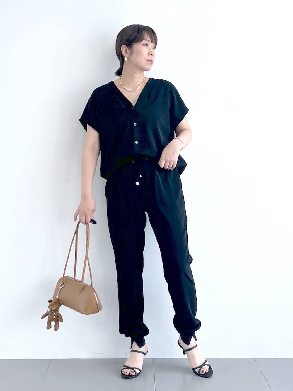 ブラウン系のハンドバッグ、ブラック系のシャツ/ブラウス、ブラック系のサンダルを着用したレディースの春コーディネートの2枚目の写真