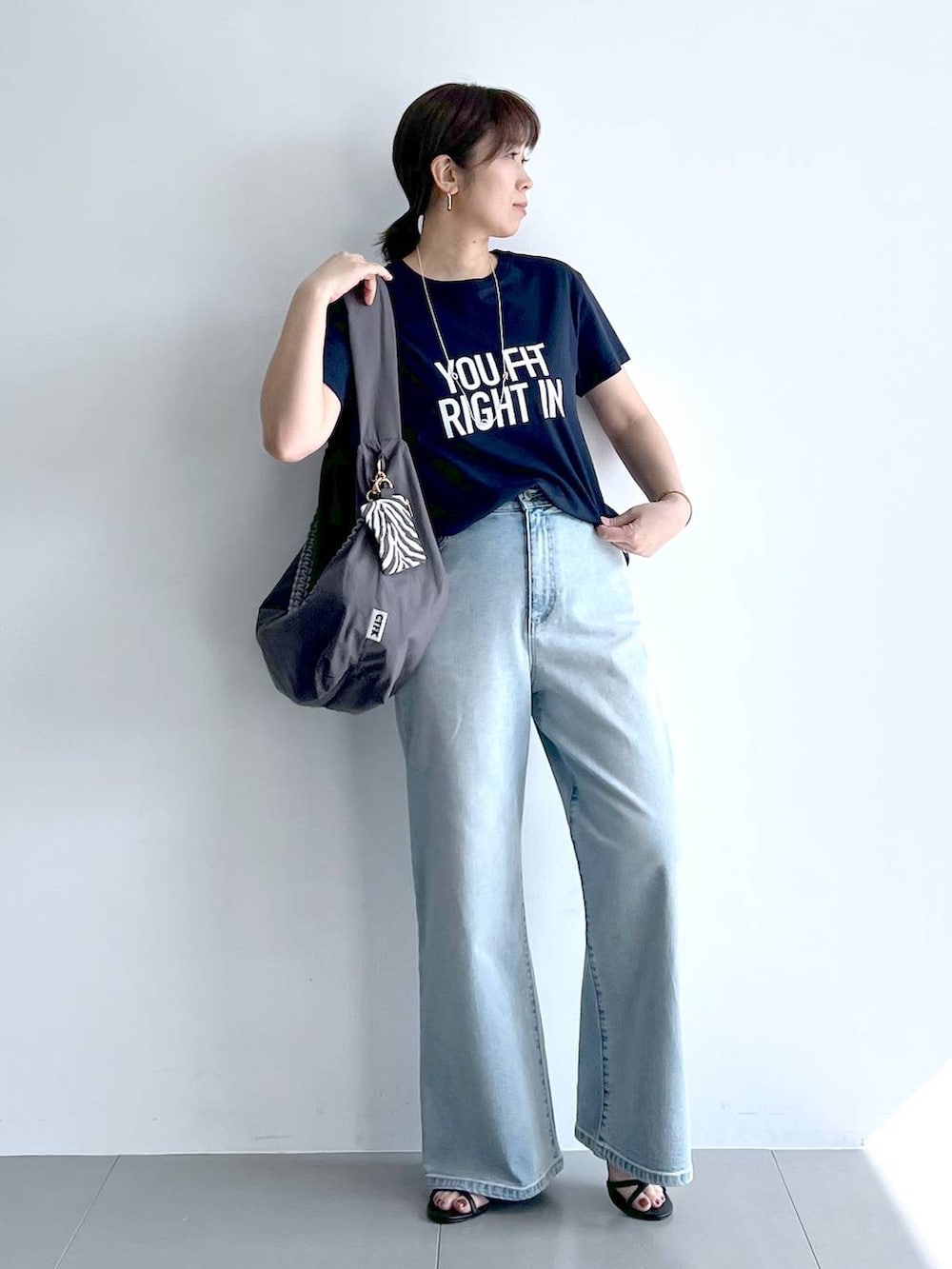 ブルー系のデニムパンツ、グレー系のショルダーバッグ、ブラック系のサンダルを着用したレディースの夏コーディネートの5枚目の写真