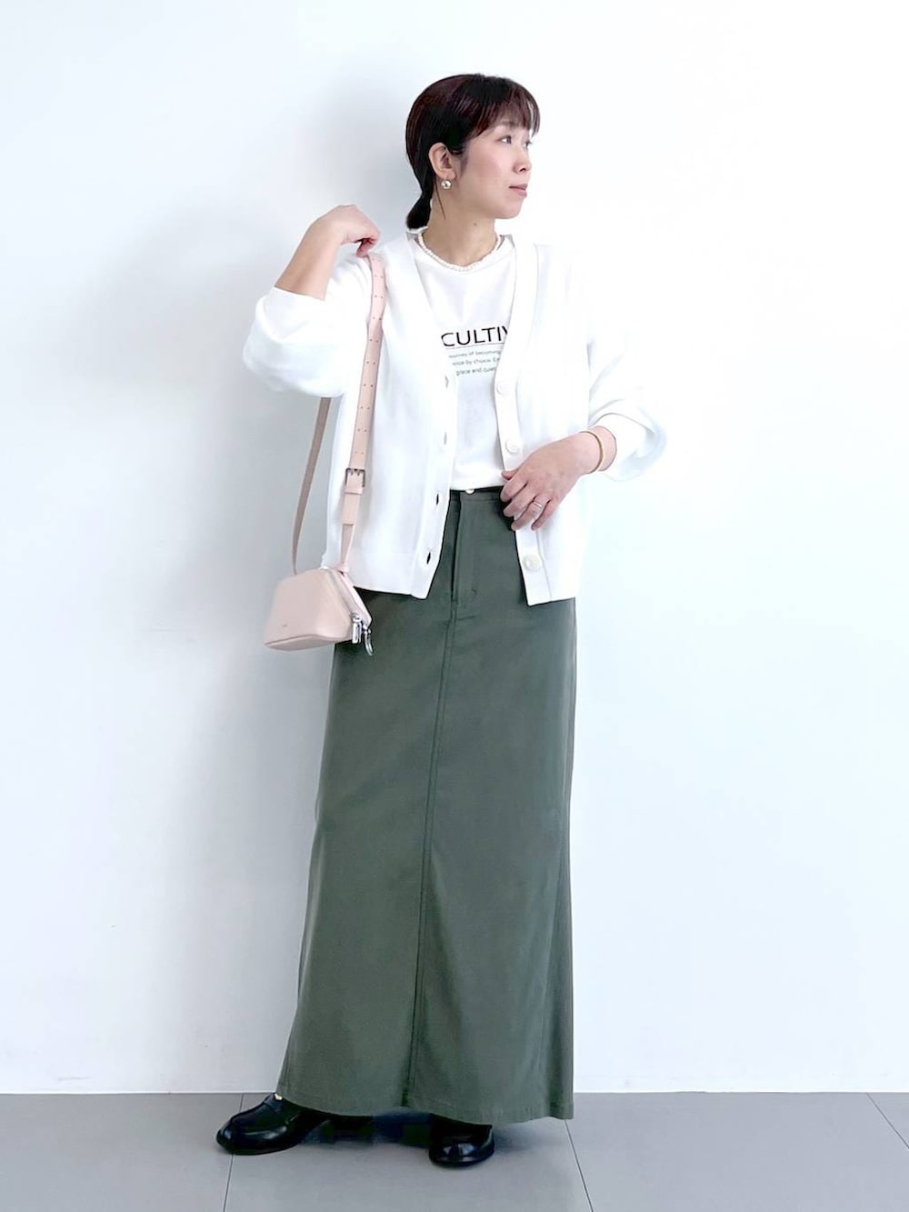 ホワイト系のTシャツ/カットソー、グリーン系のスカート、ピンク系のショルダーバッグを着用したレディースの冬コーディネートの2枚目の写真