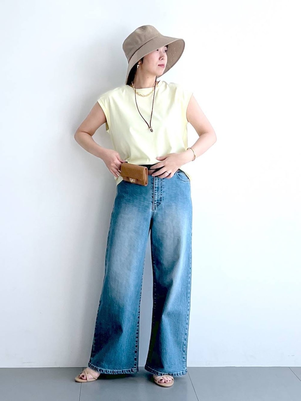 ブルー系のデニムパンツ、イエロー系のTシャツ/カットソー、ベージュ系のショルダーバッグを着用したレディースの春コーディネートの3枚目の写真