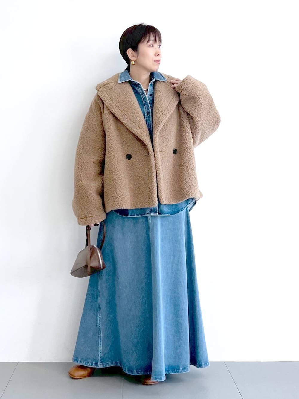 イエロー系のピーコート、ブルー系のシャツ/ブラウス、ブラウン系のショルダーバッグを着用したレディースの秋コーディネートの4枚目の写真