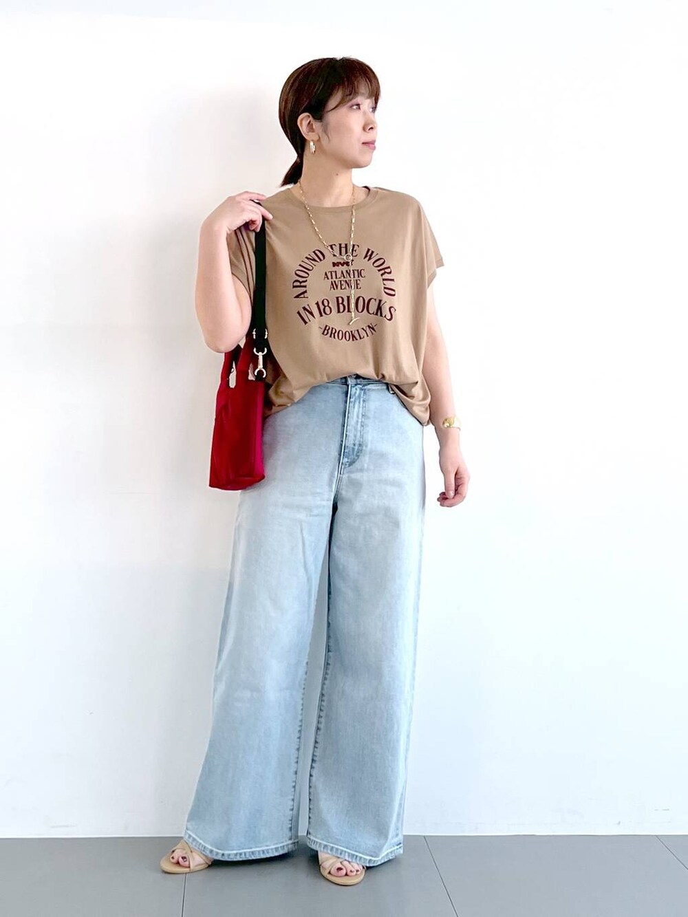 ブルー系のデニムパンツ、ベージュ系のサンダル、ゴールド系のネックレスを着用したレディースの春コーディネートの4枚目の写真