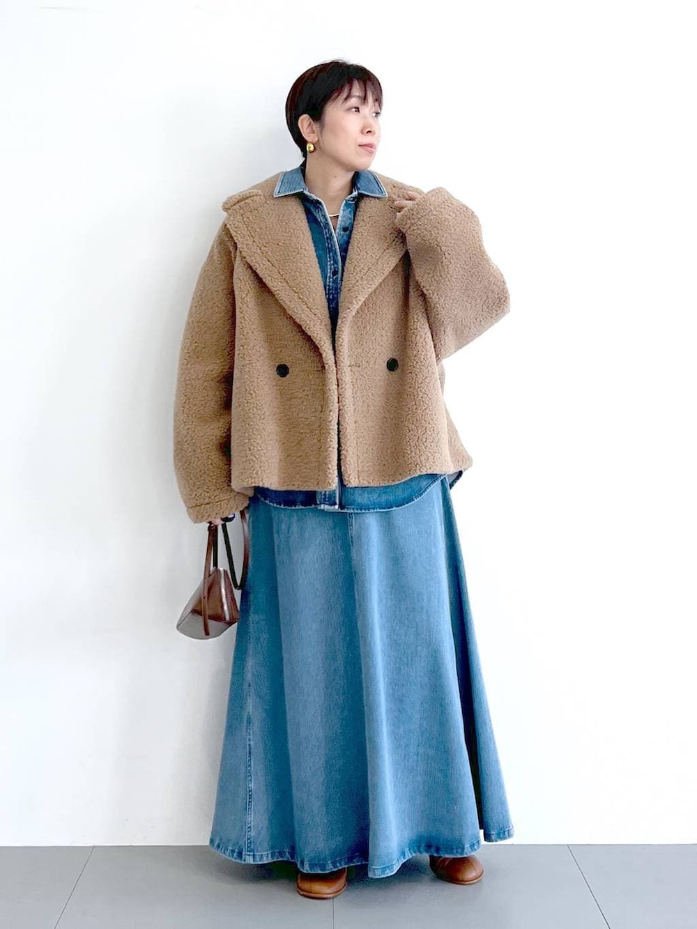 イエロー系のピーコート、ブルー系のシャツ/ブラウス、ブラウン系のショルダーバッグを着用したレディースの秋コーディネートの5枚目の写真