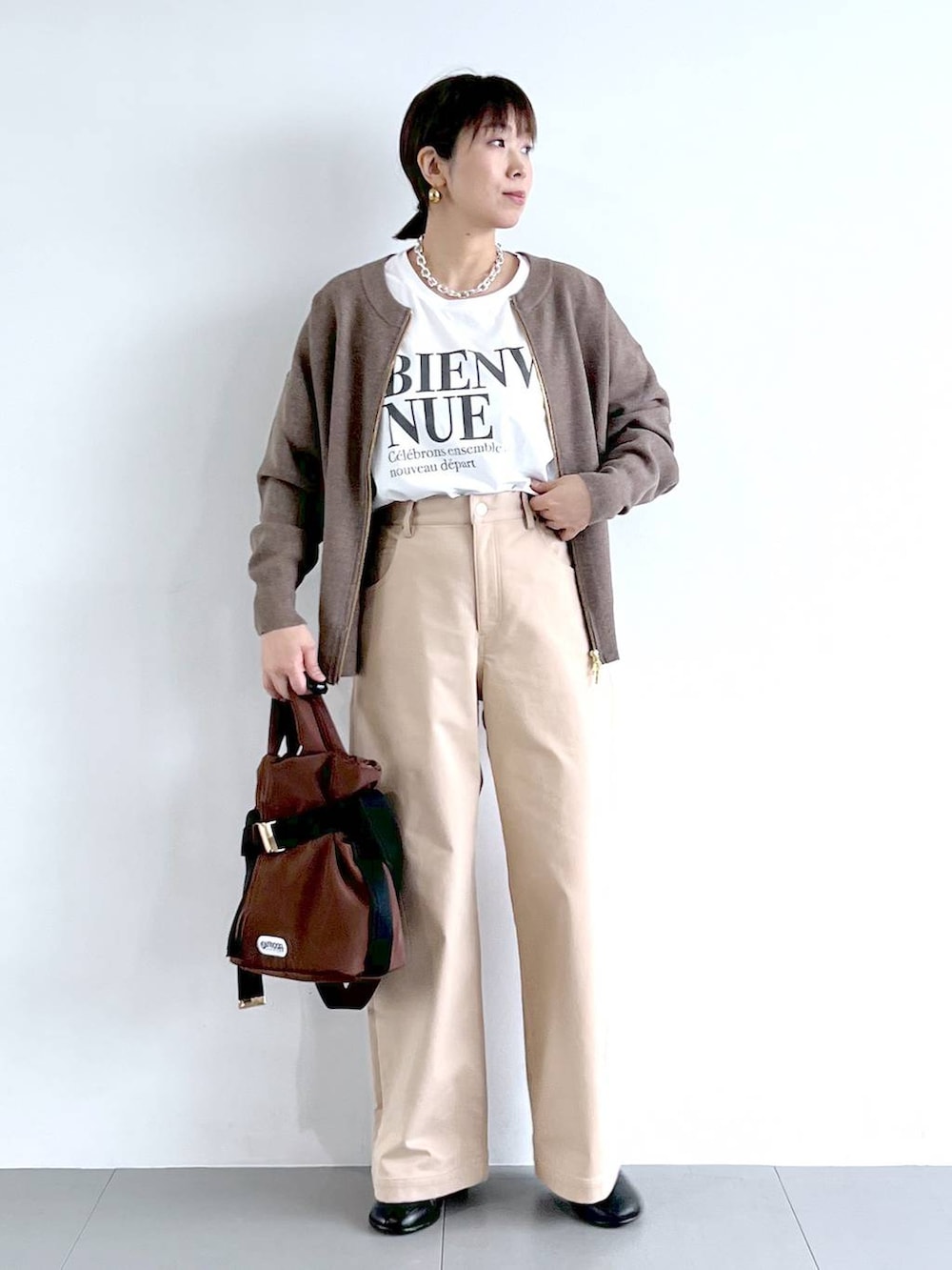 ブラウン系のショルダーバッグ、ホワイト系のTシャツ/カットソー、ブラック系のブーツを着用したレディースの秋コーディネートの2枚目の写真