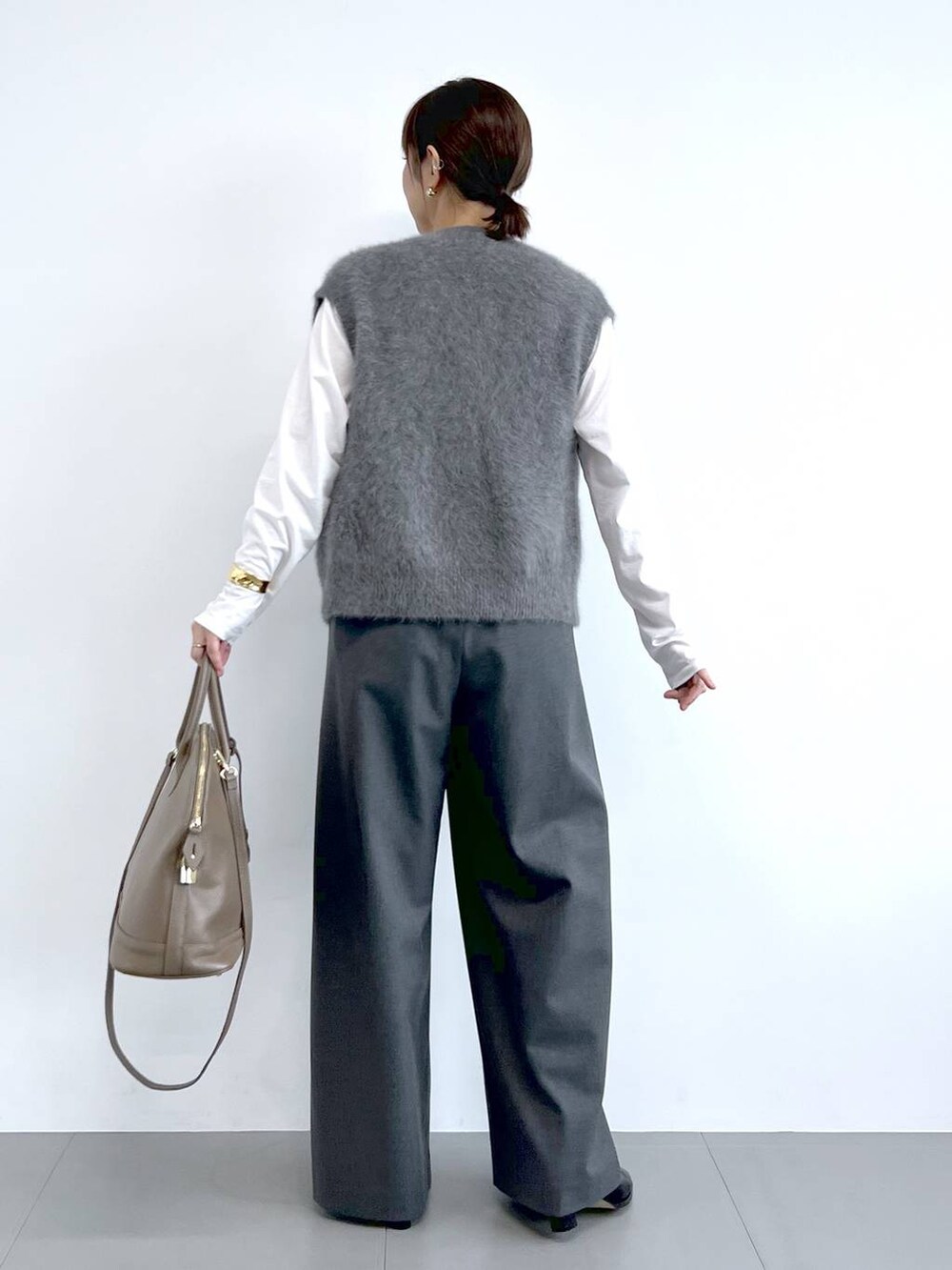 グレー系のスラックス、グレー系のベスト、ブラウン系のボストンバッグを着用したレディースの夏コーディネートの6枚目の写真