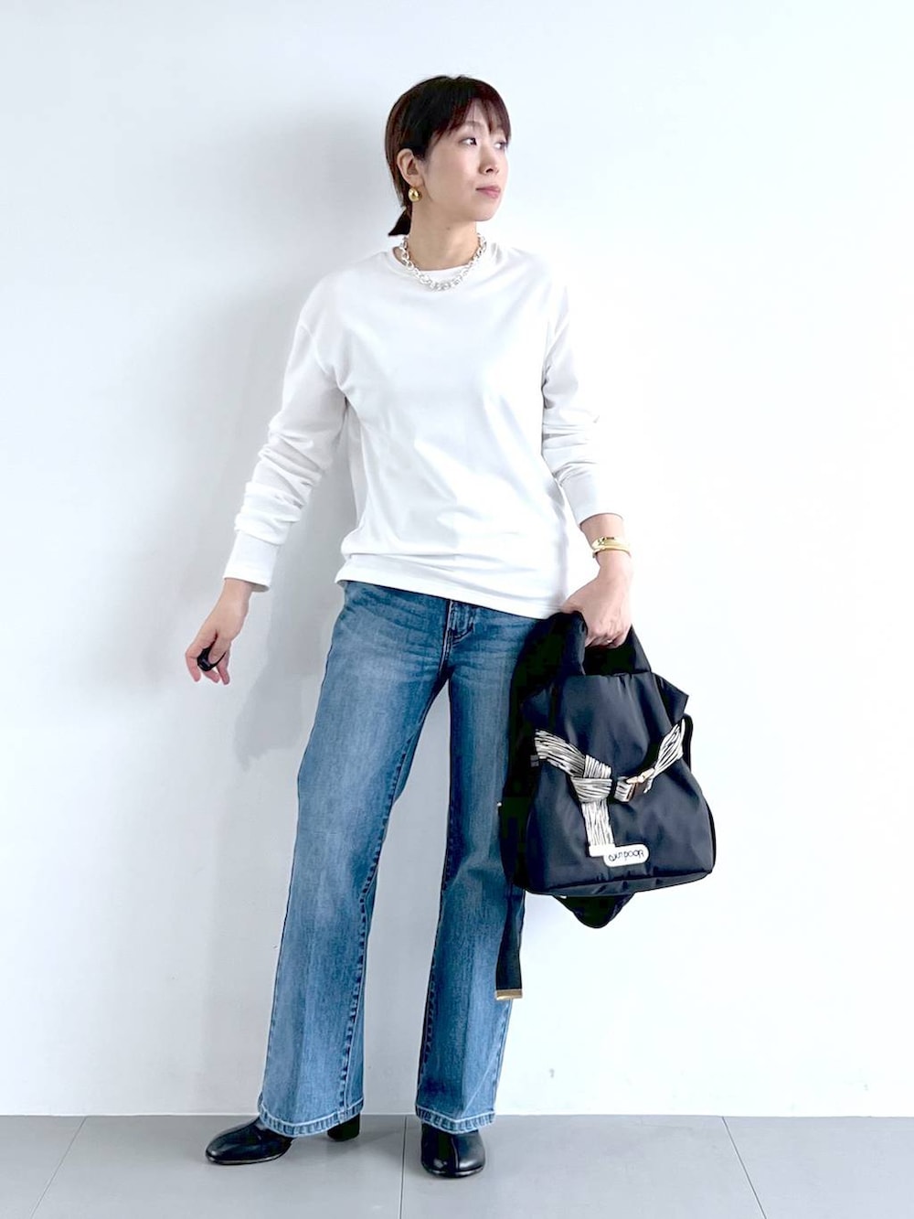 ブルー系のデニムパンツ、その他のショルダーバッグ、ブラック系のブーツを着用したレディースの秋コーディネートの3枚目の写真