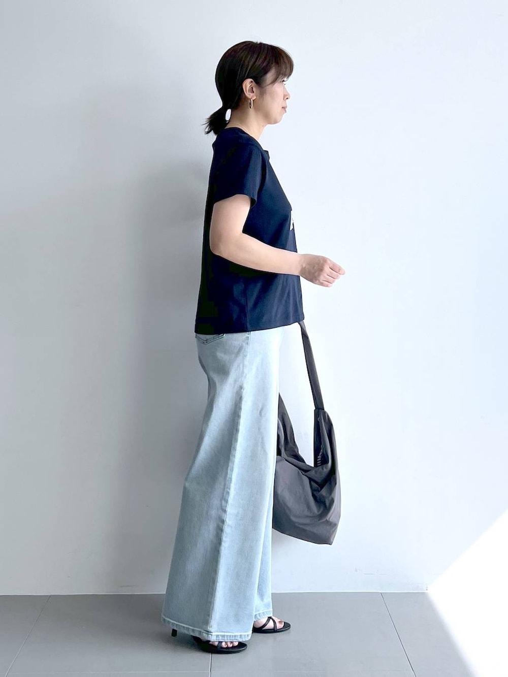 ブルー系のデニムパンツ、グレー系のショルダーバッグ、ブラック系のサンダルを着用したレディースの夏コーディネートの7枚目の写真