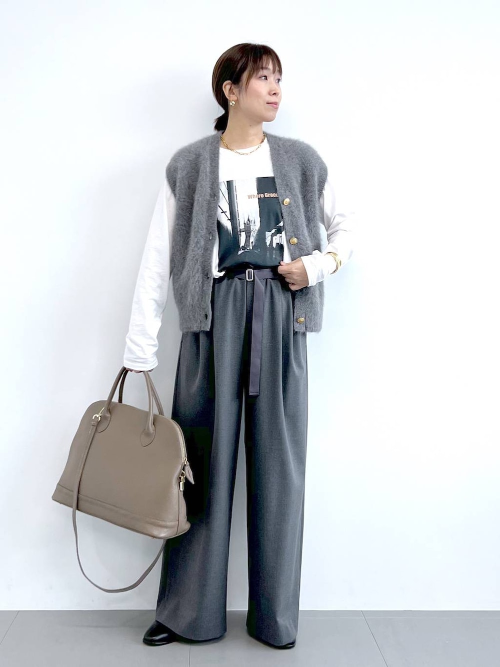 グレー系のスラックス、グレー系のベスト、ブラウン系のボストンバッグを着用したレディースの夏コーディネートの2枚目の写真