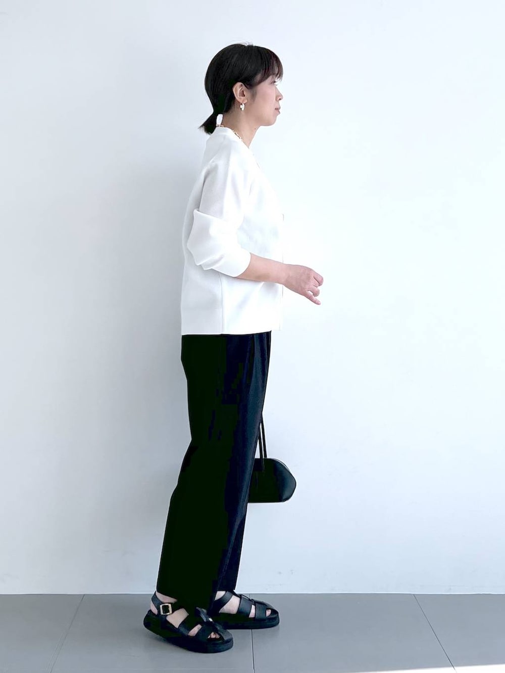 ブラック系のその他パンツ、ブラック系のハンドバッグ、ホワイト系のカーディガン/ボレロを着用したレディースの春コーディネートの9枚目の写真