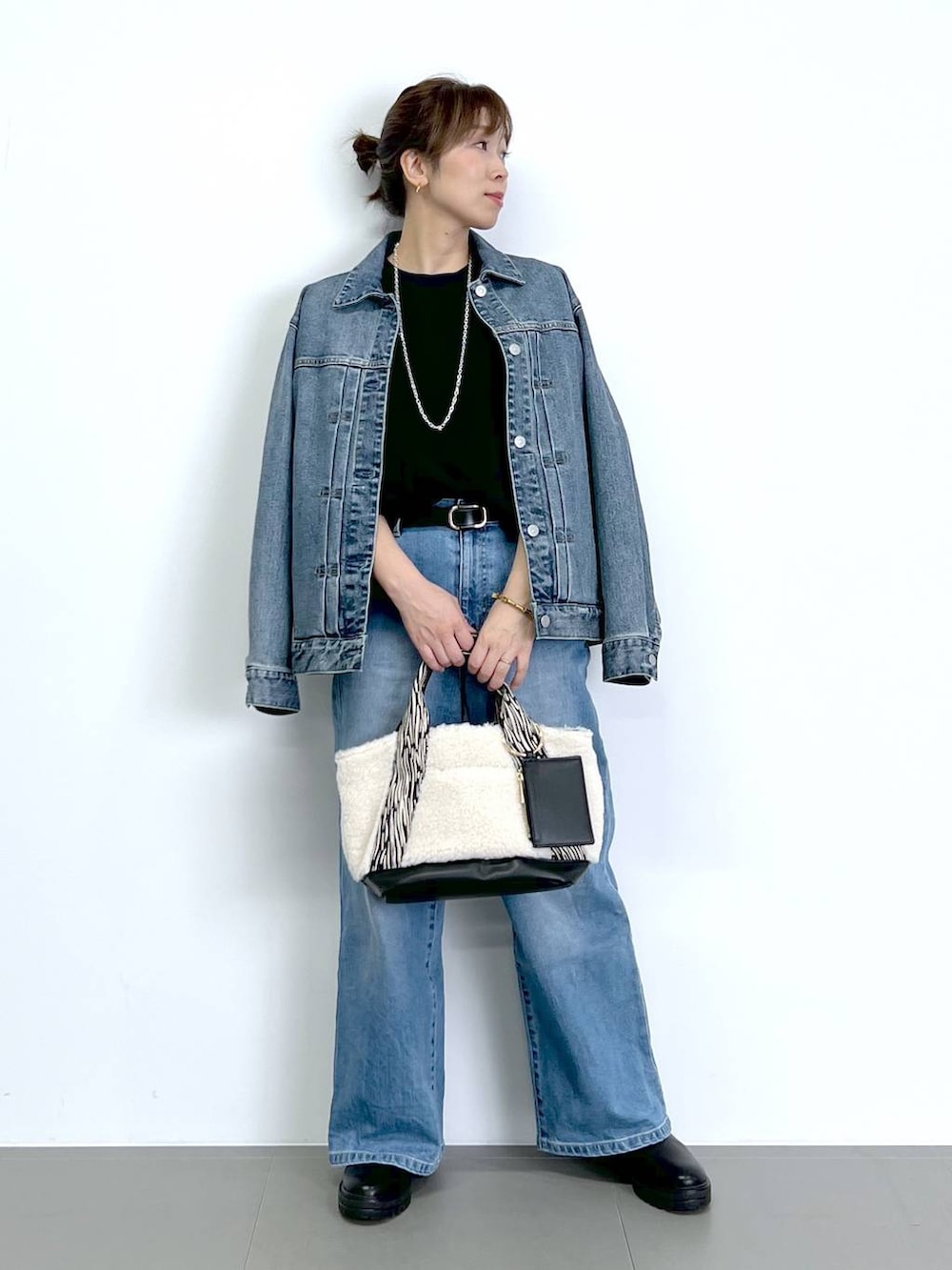 ブルー系のデニムパンツ、ブラック系のTシャツ/カットソー、ブラック系のブーツを着用したレディースの秋コーディネートの3枚目の写真