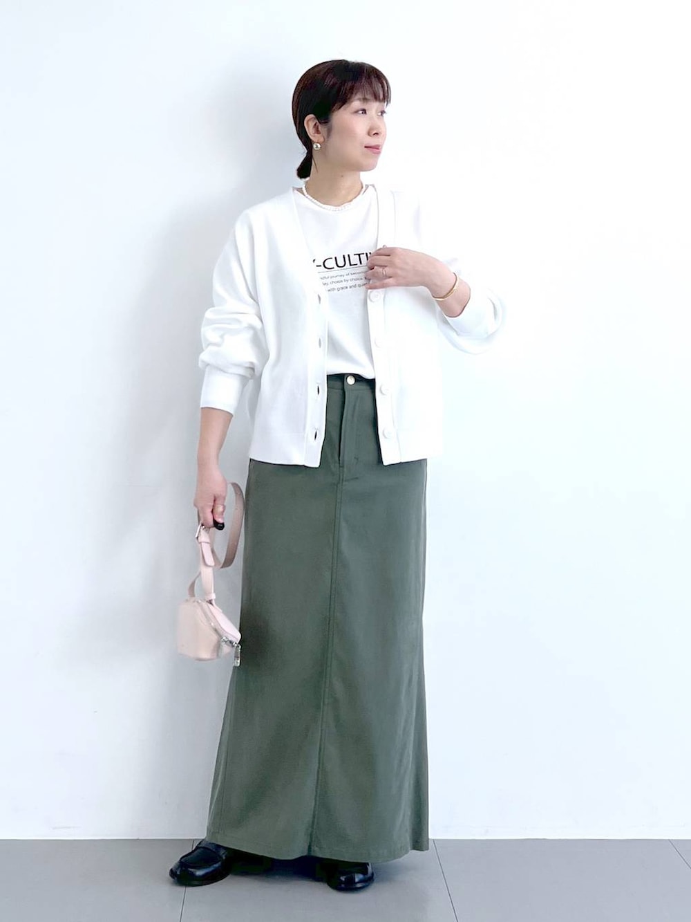 ホワイト系のTシャツ/カットソー、グリーン系のスカート、ピンク系のショルダーバッグを着用したレディースの冬コーディネートの3枚目の写真