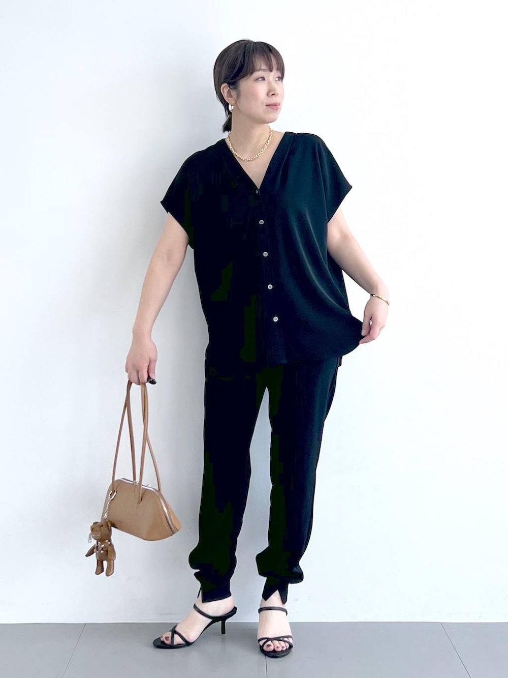 ブラウン系のハンドバッグ、ブラック系のシャツ/ブラウス、ブラック系のサンダルを着用したレディースの春コーディネートの6枚目の写真