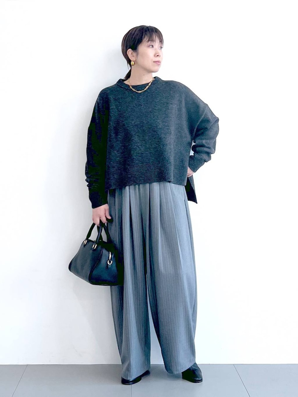 ブラック系のボストンバッグ、ブラック系のブーツ、グレー系のニット/セーターを着用したレディースの秋コーディネートの3枚目の写真