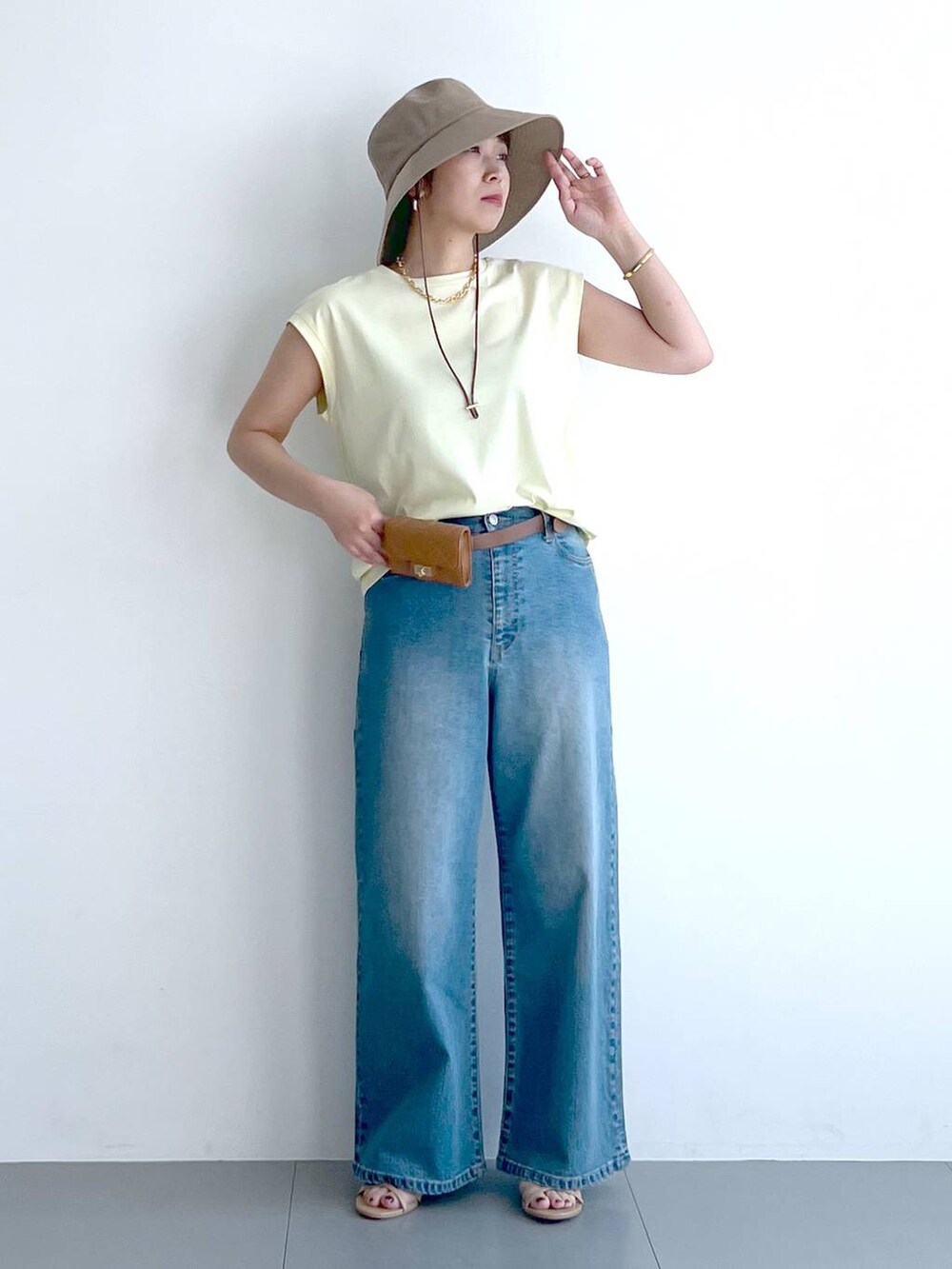 ブルー系のデニムパンツ、イエロー系のTシャツ/カットソー、ベージュ系のショルダーバッグを着用したレディースの春コーディネートの7枚目の写真