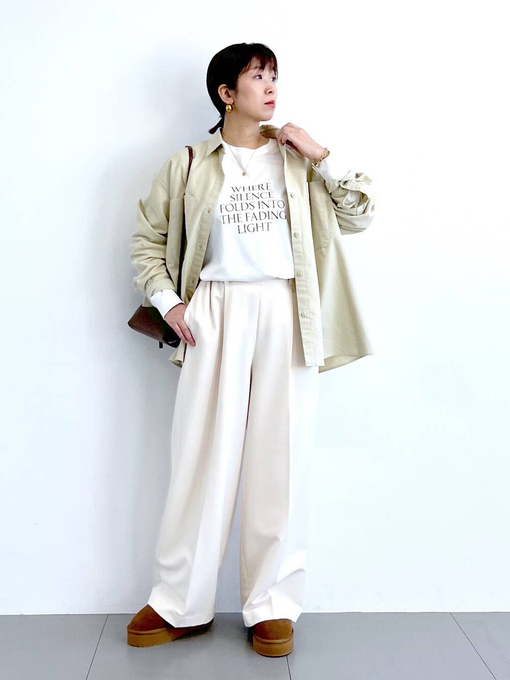 ブラウン系のショルダーバッグ、イエロー系のブーツ、ホワイト系のTシャツ/カットソーを着用したレディースの冬コーディネートの4枚目の写真