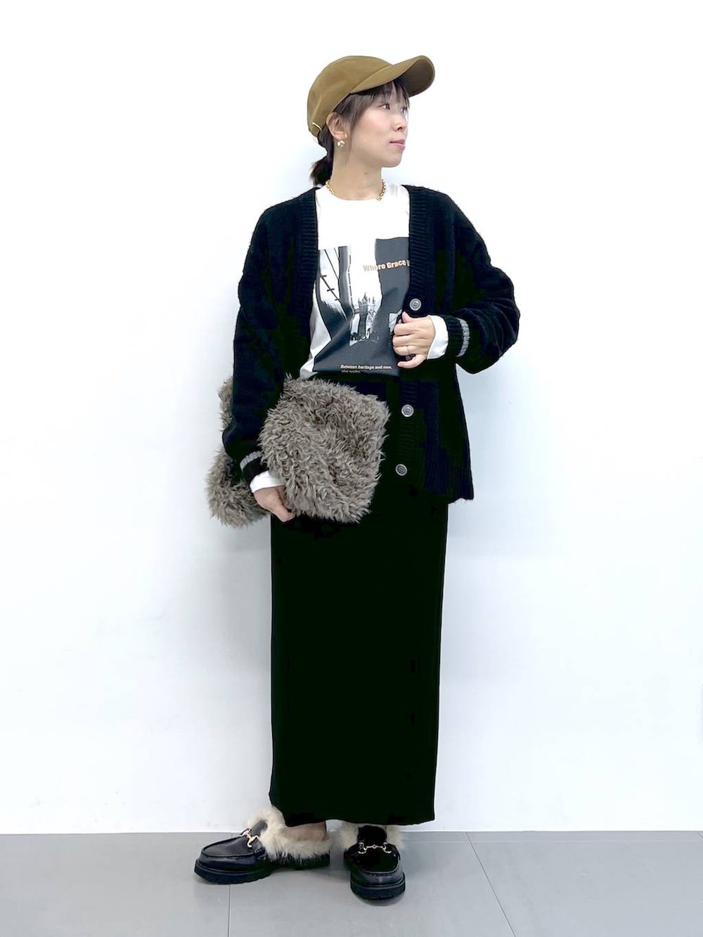 ブラック系のスカート、ブラック系のカーディガン/ボレロ、ブラウン系のハンドバッグを着用したレディースの秋コーディネートの2枚目の写真