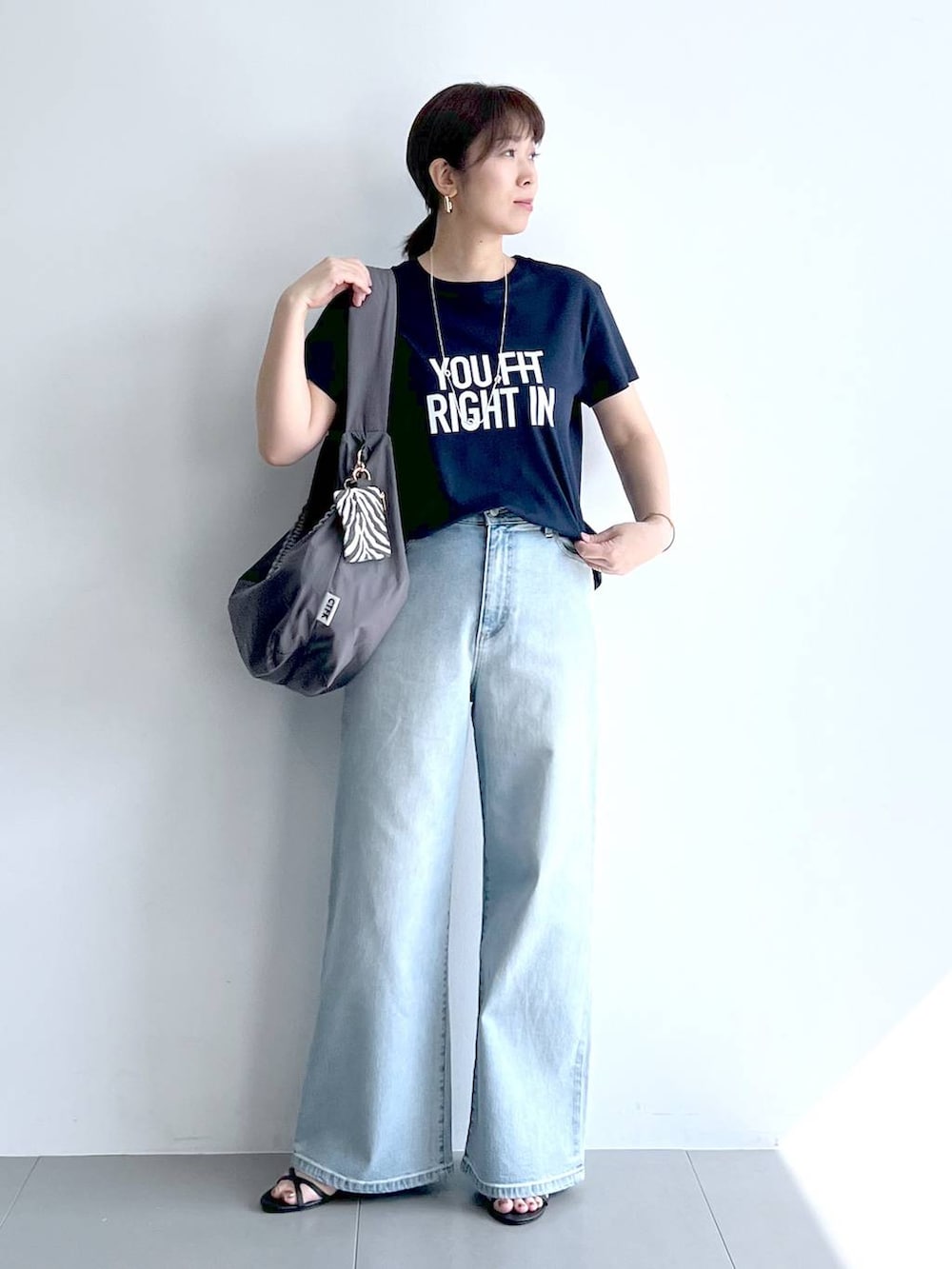 ブルー系のデニムパンツ、グレー系のショルダーバッグ、ブラック系のサンダルを着用したレディースの夏コーディネートの4枚目の写真