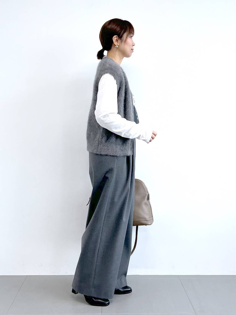 グレー系のスラックス、グレー系のベスト、ブラウン系のボストンバッグを着用したレディースの夏コーディネートの5枚目の写真