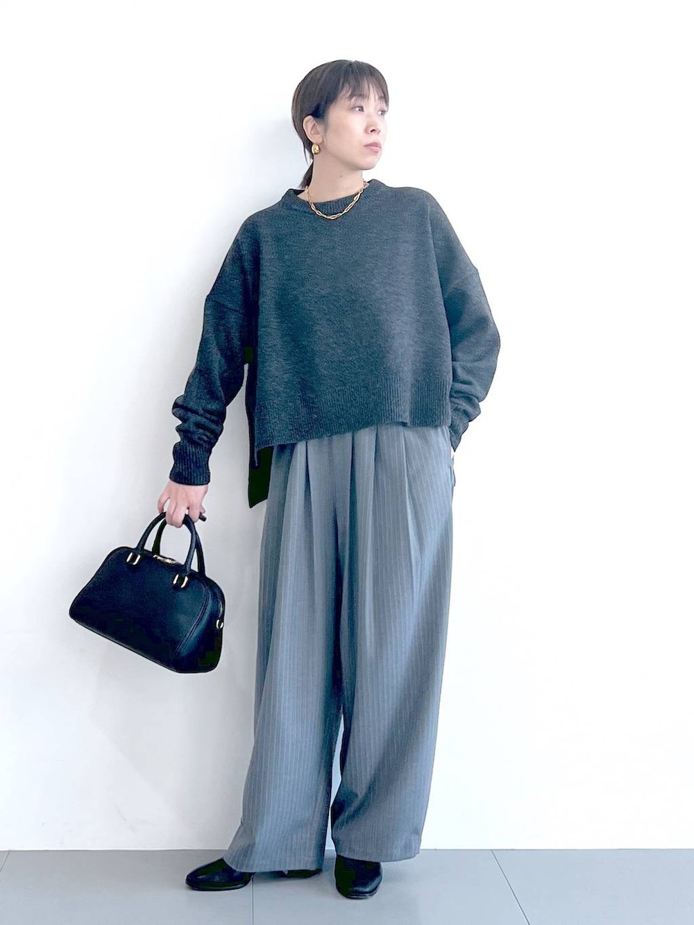 ブラック系のボストンバッグ、ブラック系のブーツ、グレー系のニット/セーターを着用したレディースの秋コーディネートの4枚目の写真