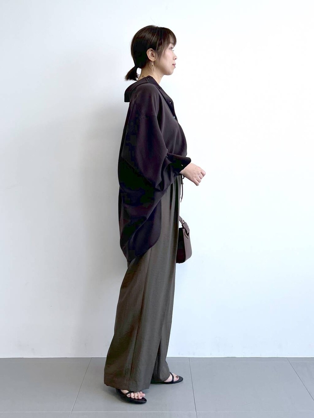 ブラウン系のハンドバッグ、ブラック系のサンダル、ブラウン系のシャツ/ブラウスを着用したレディースの夏コーディネートの6枚目の写真