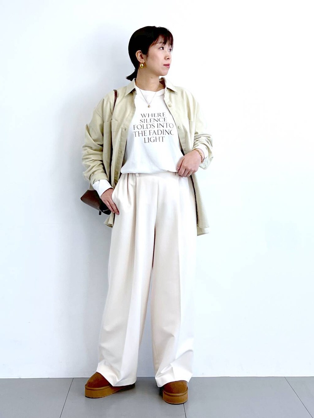 ブラウン系のショルダーバッグ、イエロー系のブーツ、ホワイト系のTシャツ/カットソーを着用したレディースの冬コーディネートの6枚目の写真