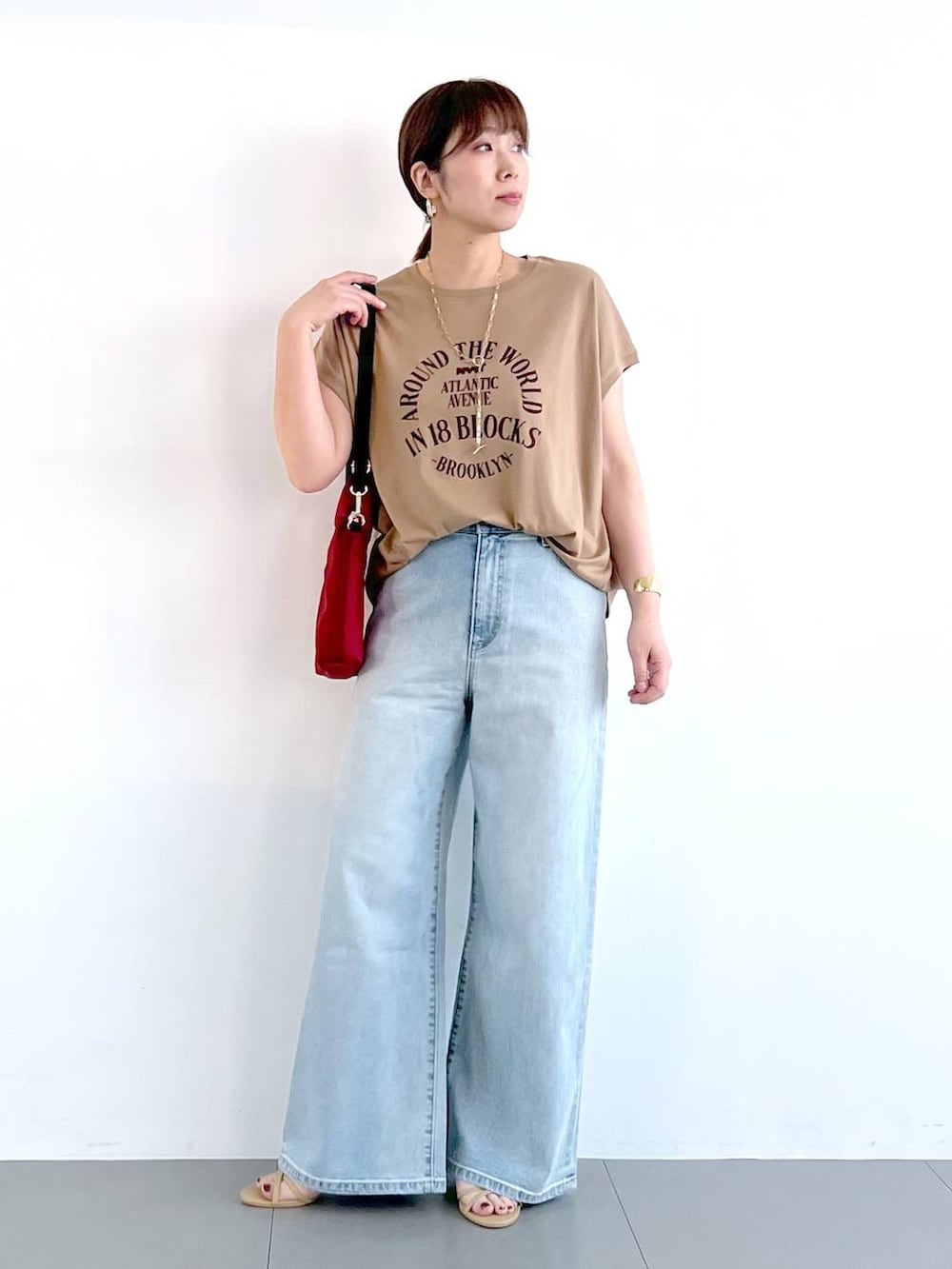 ブルー系のデニムパンツ、ベージュ系のサンダル、ゴールド系のネックレスを着用したレディースの春コーディネートの3枚目の写真