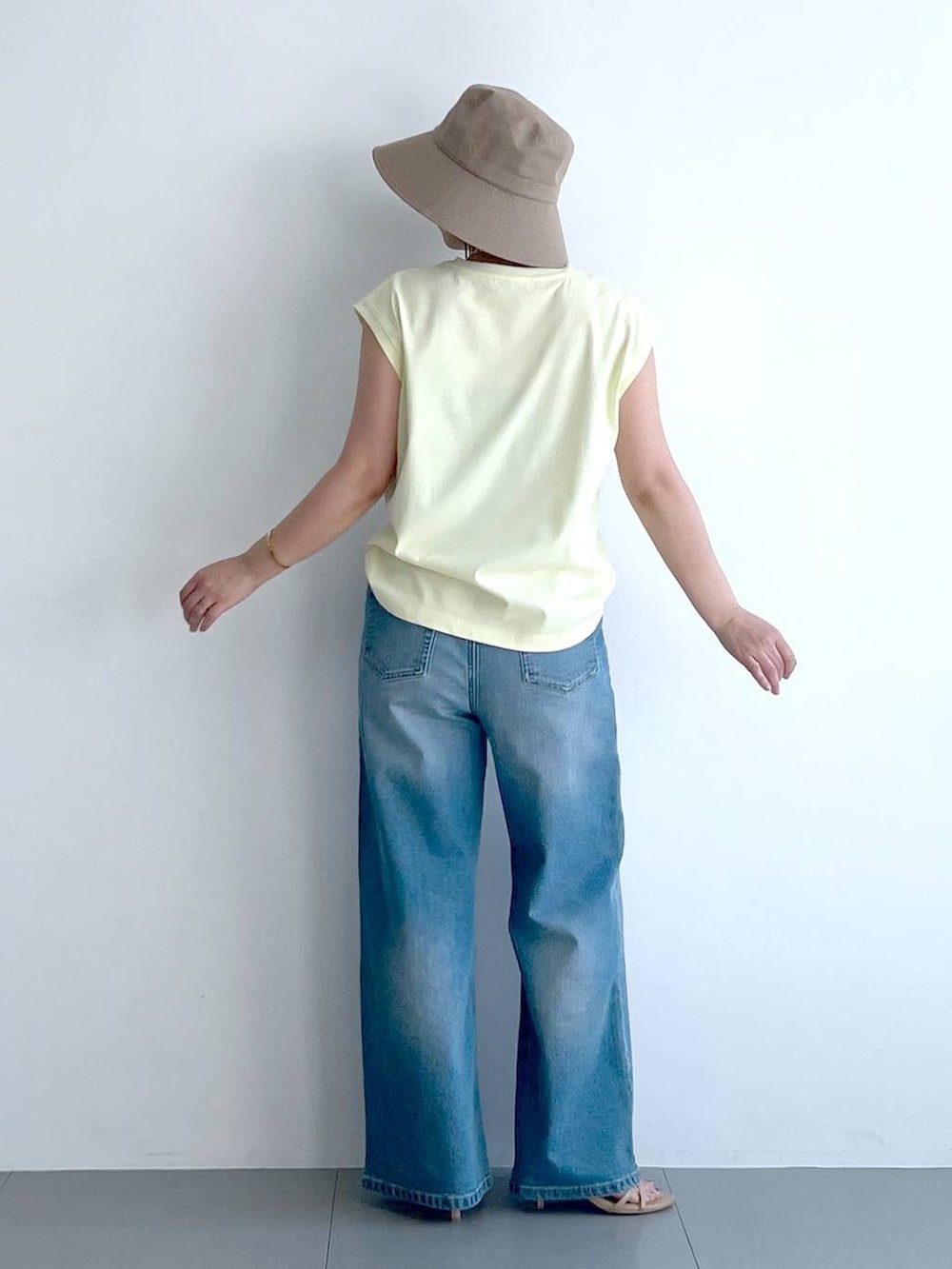 ブルー系のデニムパンツ、イエロー系のTシャツ/カットソー、ベージュ系のショルダーバッグを着用したレディースの春コーディネートの9枚目の写真