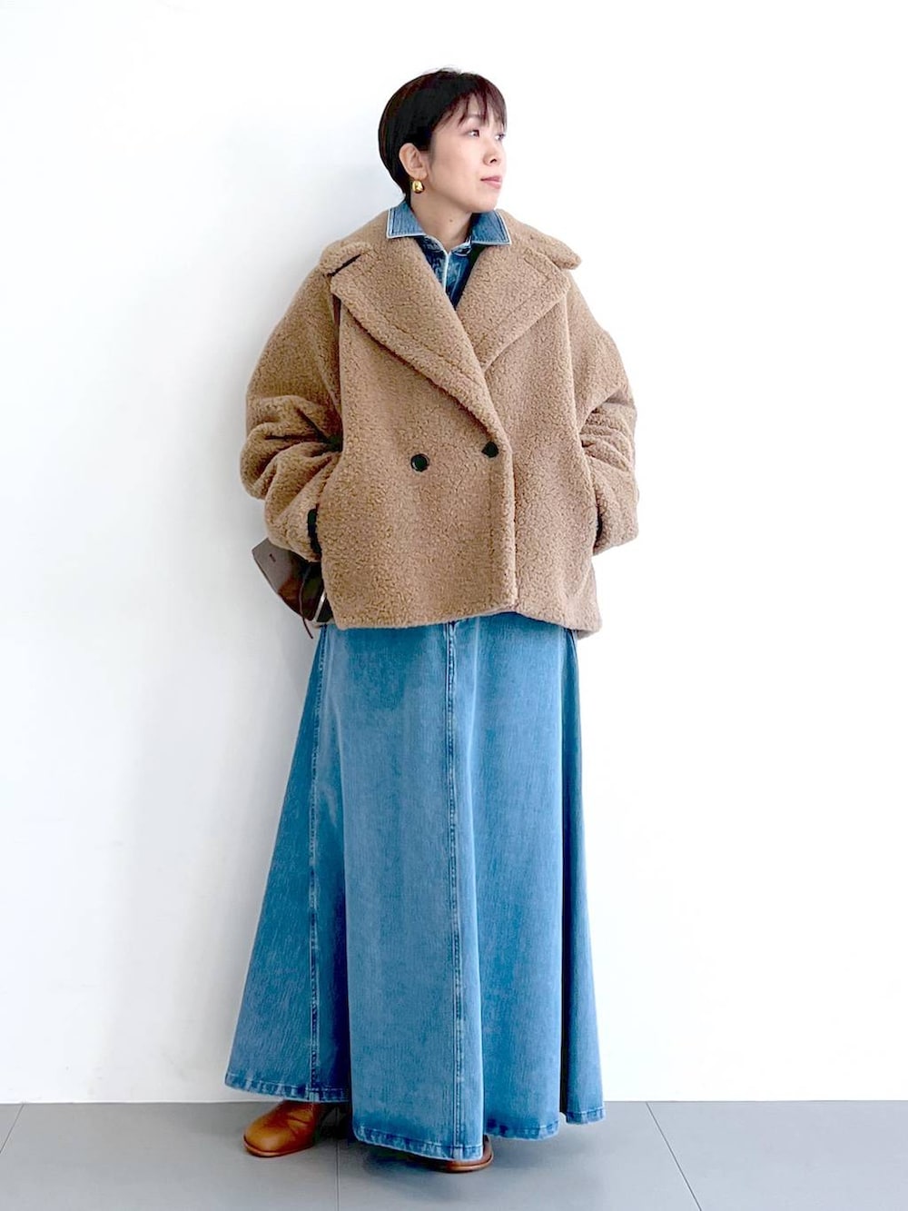 イエロー系のピーコート、ブルー系のシャツ/ブラウス、ブラウン系のショルダーバッグを着用したレディースの秋コーディネートの3枚目の写真