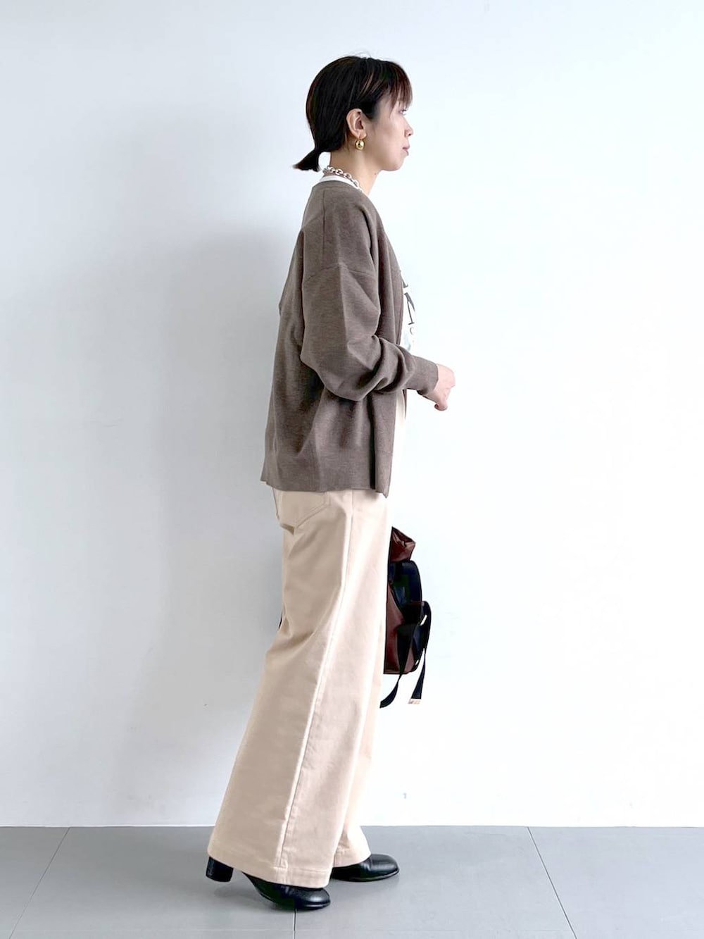 ブラウン系のショルダーバッグ、ホワイト系のTシャツ/カットソー、ブラック系のブーツを着用したレディースの秋コーディネートの5枚目の写真