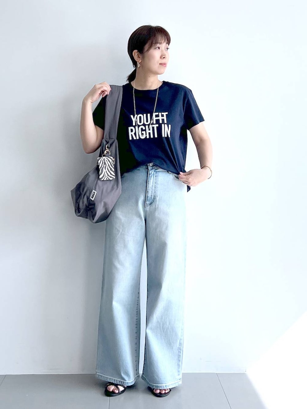 ブルー系のデニムパンツ、グレー系のショルダーバッグ、ブラック系のサンダルを着用したレディースの夏コーディネートの2枚目の写真