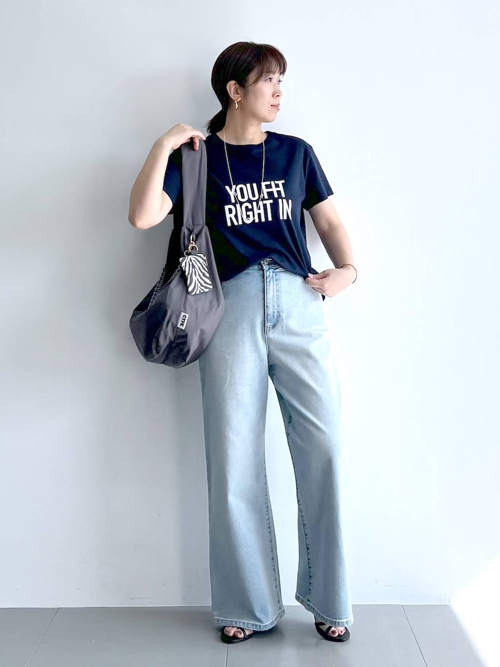 ブルー系のデニムパンツ、グレー系のショルダーバッグ、ブラック系のサンダルを着用したレディースの夏コーディネートの6枚目の写真