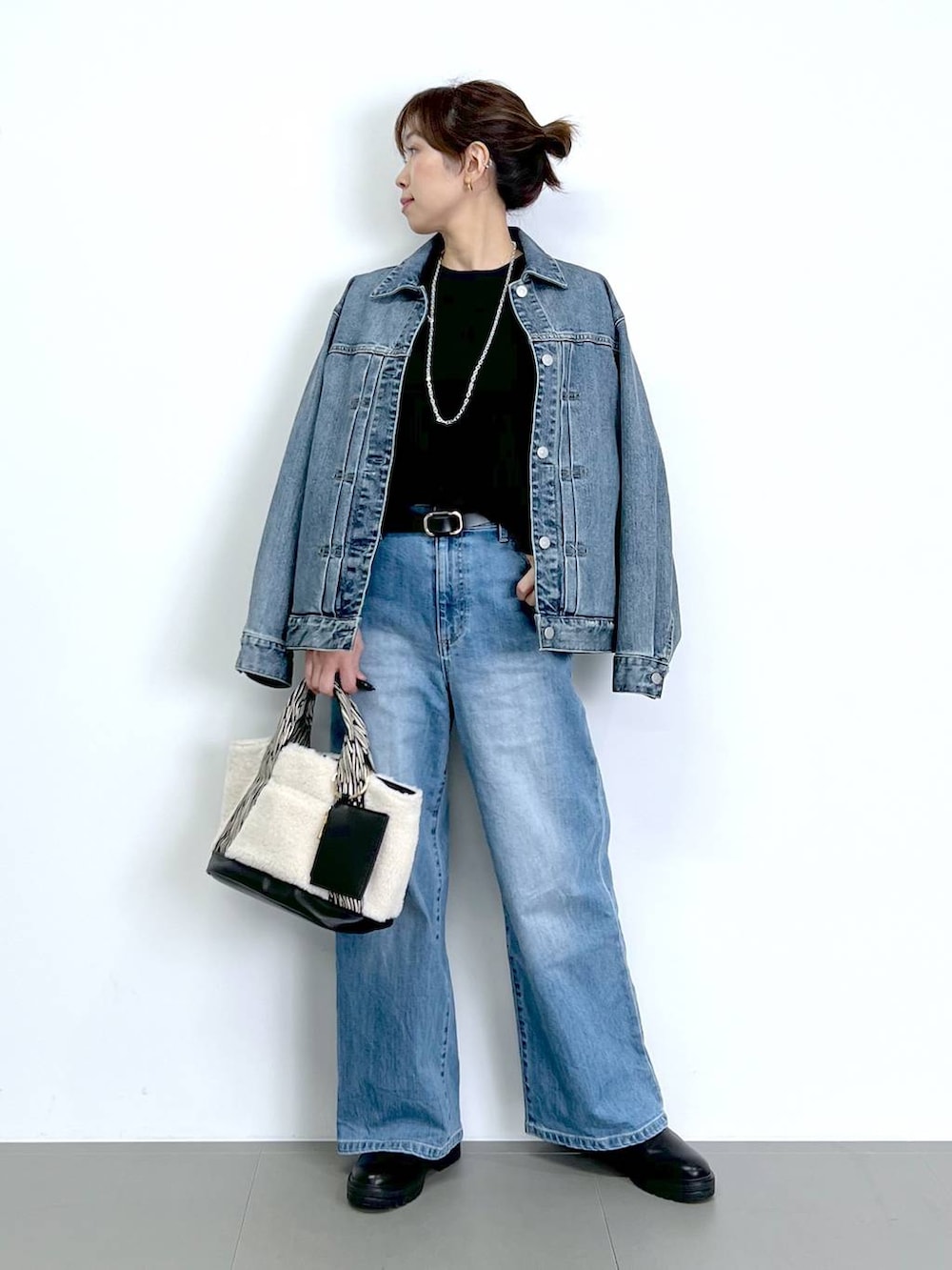 ブルー系のデニムパンツ、ブラック系のTシャツ/カットソー、ブラック系のブーツを着用したレディースの秋コーディネートの4枚目の写真