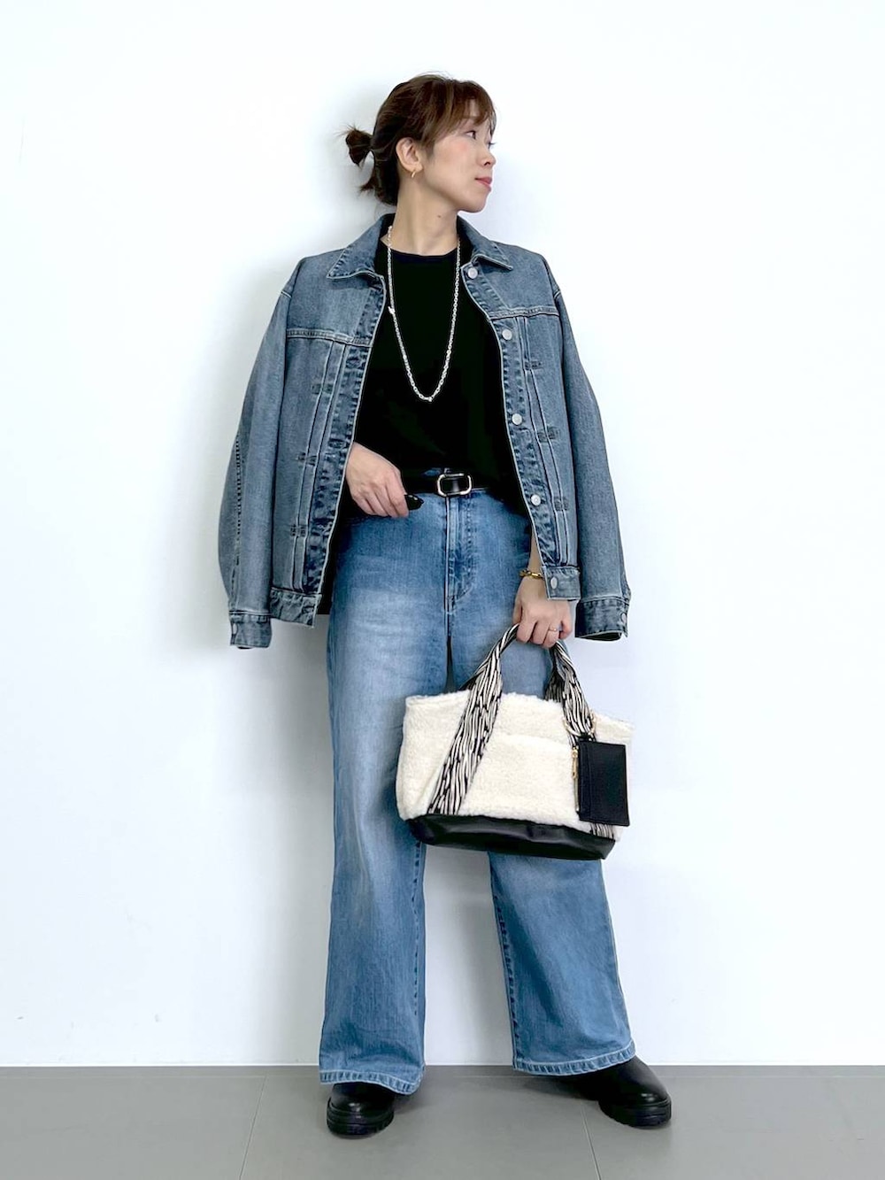 ブルー系のデニムパンツ、ブラック系のTシャツ/カットソー、ブラック系のブーツを着用したレディースの秋コーディネートの2枚目の写真