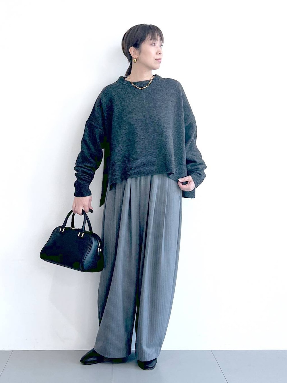 ブラック系のボストンバッグ、ブラック系のブーツ、グレー系のニット/セーターを着用したレディースの秋コーディネートの2枚目の写真