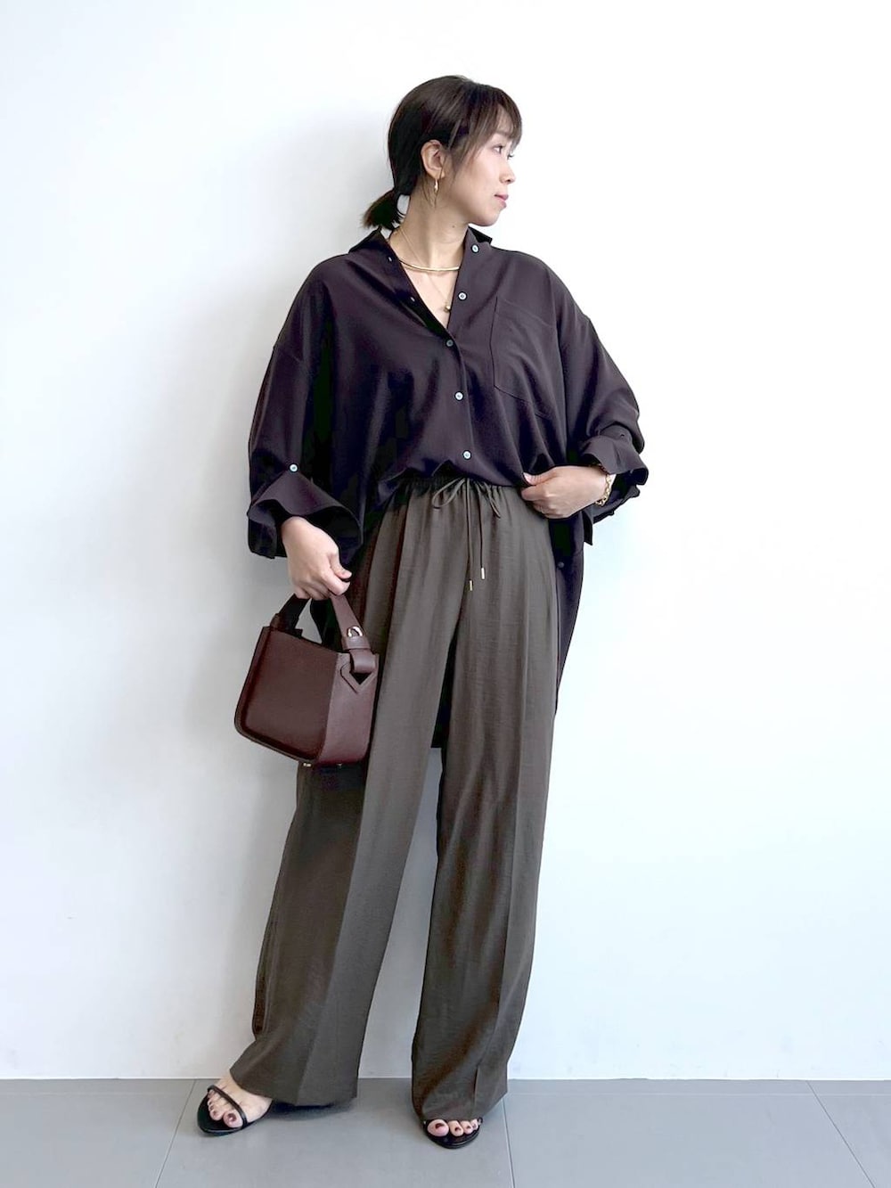 ブラウン系のハンドバッグ、ブラック系のサンダル、ブラウン系のシャツ/ブラウスを着用したレディースの夏コーディネートの4枚目の写真