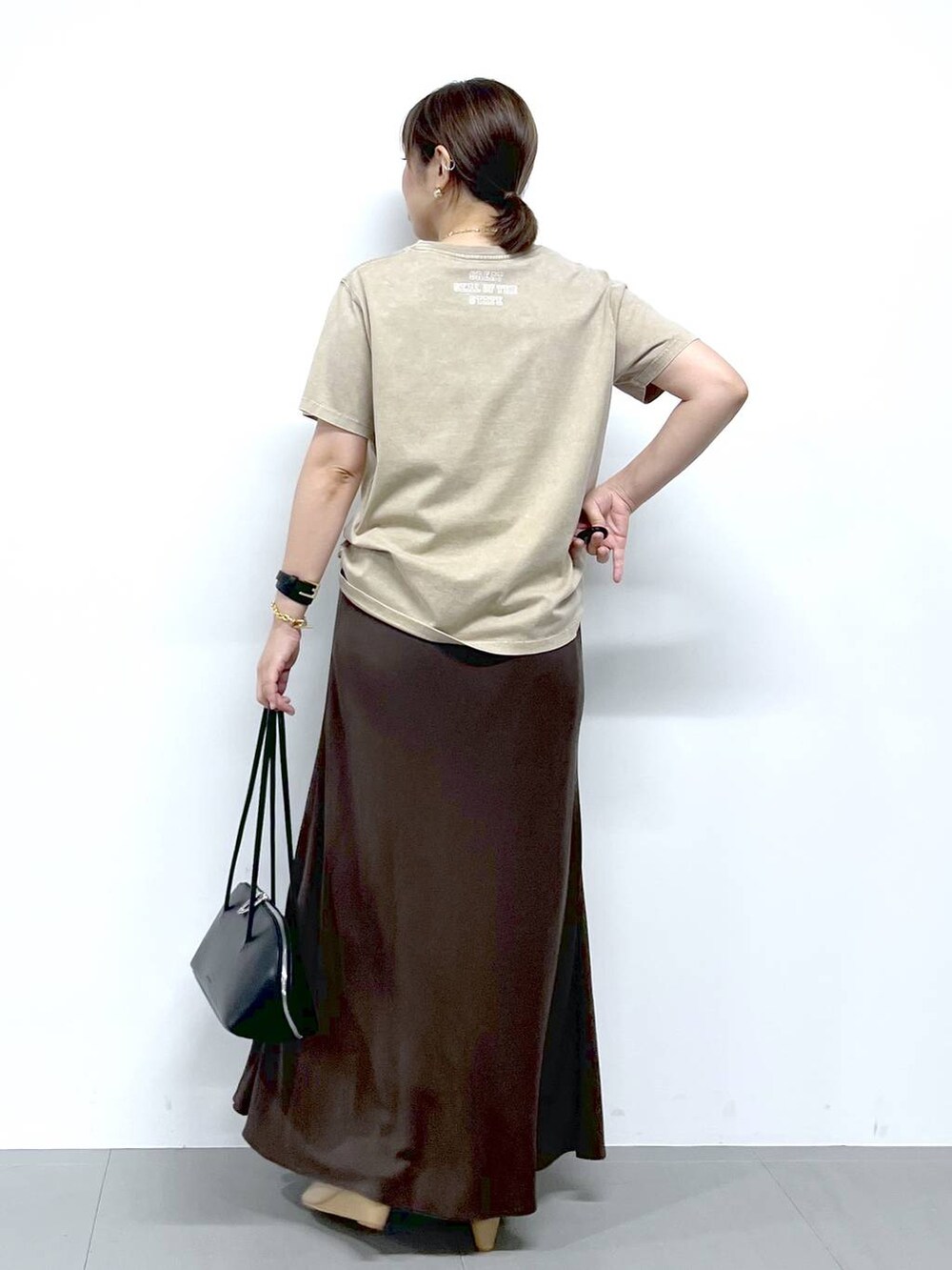 ブラック系のトートバッグ、ベージュ系のサンダル、ベージュ系のTシャツ/カットソーを着用したレディースの夏コーディネートの7枚目の写真