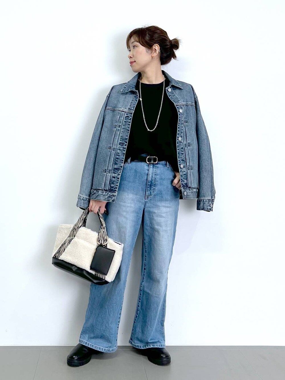 ブルー系のデニムパンツ、ブラック系のTシャツ/カットソー、ブラック系のブーツを着用したレディースの秋コーディネートの5枚目の写真