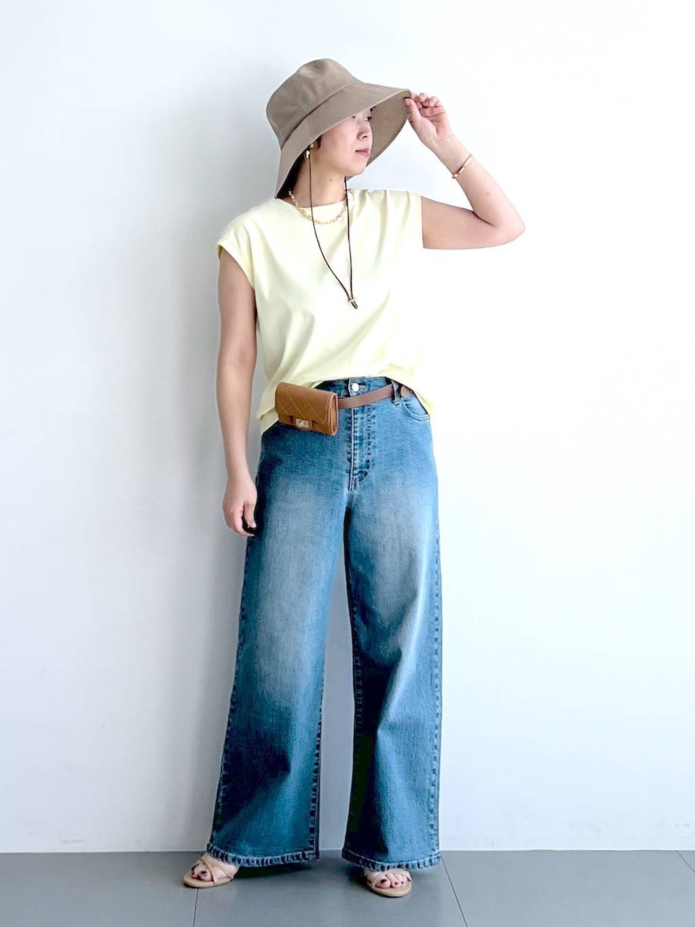 ブルー系のデニムパンツ、イエロー系のTシャツ/カットソー、ベージュ系のショルダーバッグを着用したレディースの春コーディネートの2枚目の写真