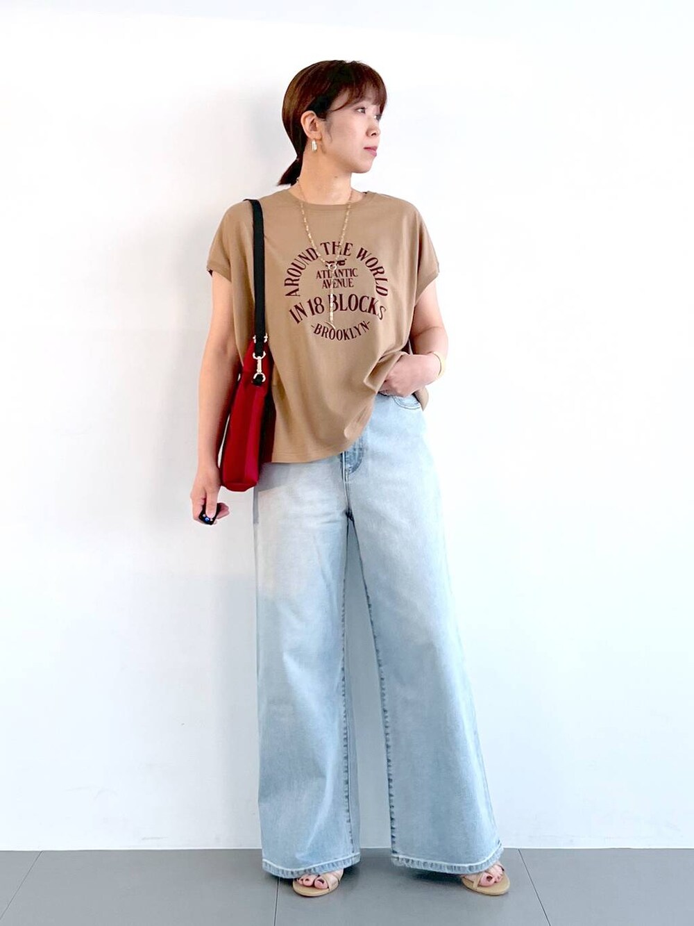 ブルー系のデニムパンツ、ベージュ系のサンダル、ゴールド系のネックレスを着用したレディースの春コーディネートの7枚目の写真