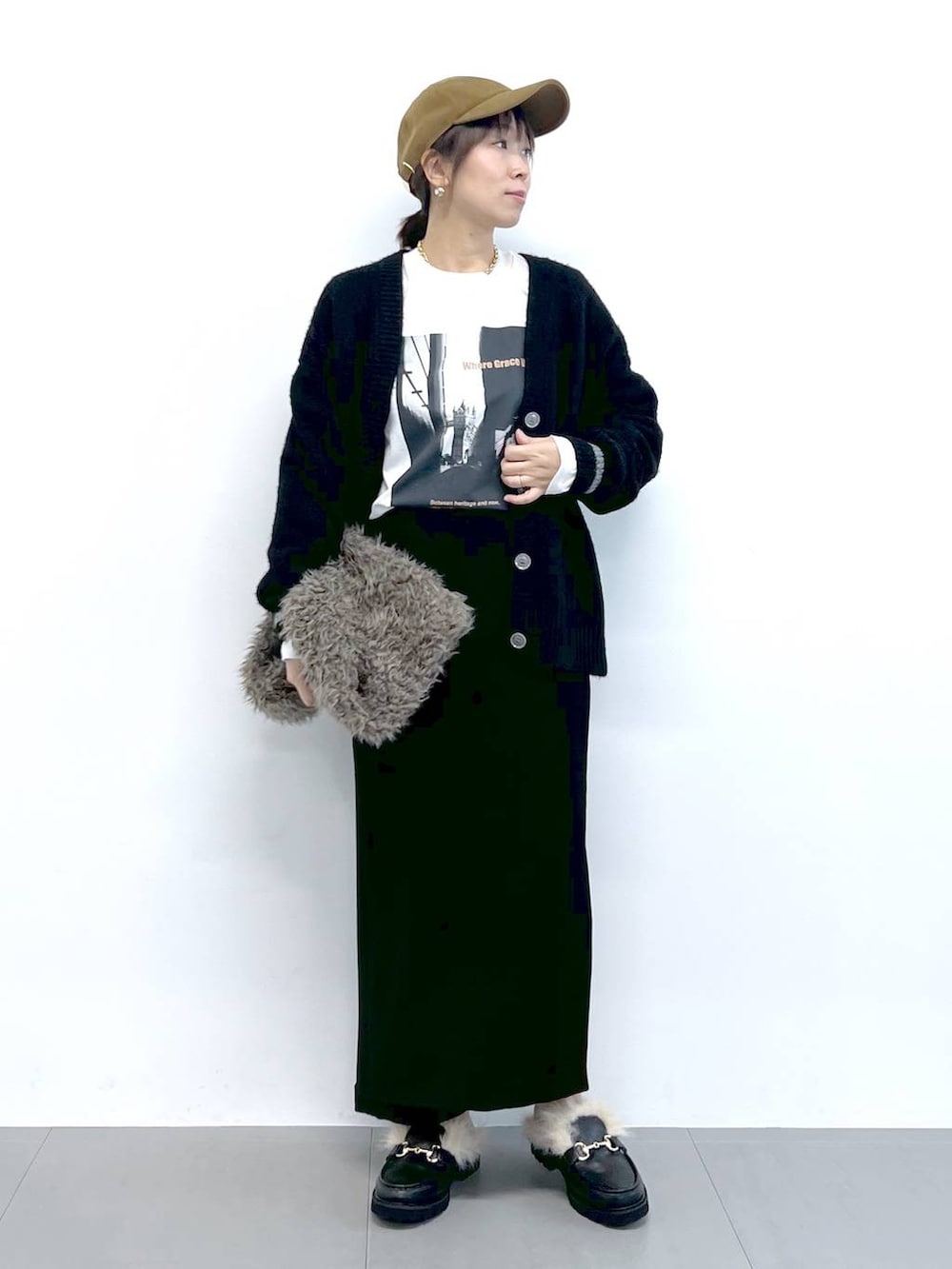 ブラック系のスカート、ブラック系のカーディガン/ボレロ、ブラウン系のハンドバッグを着用したレディースの秋コーディネートの3枚目の写真