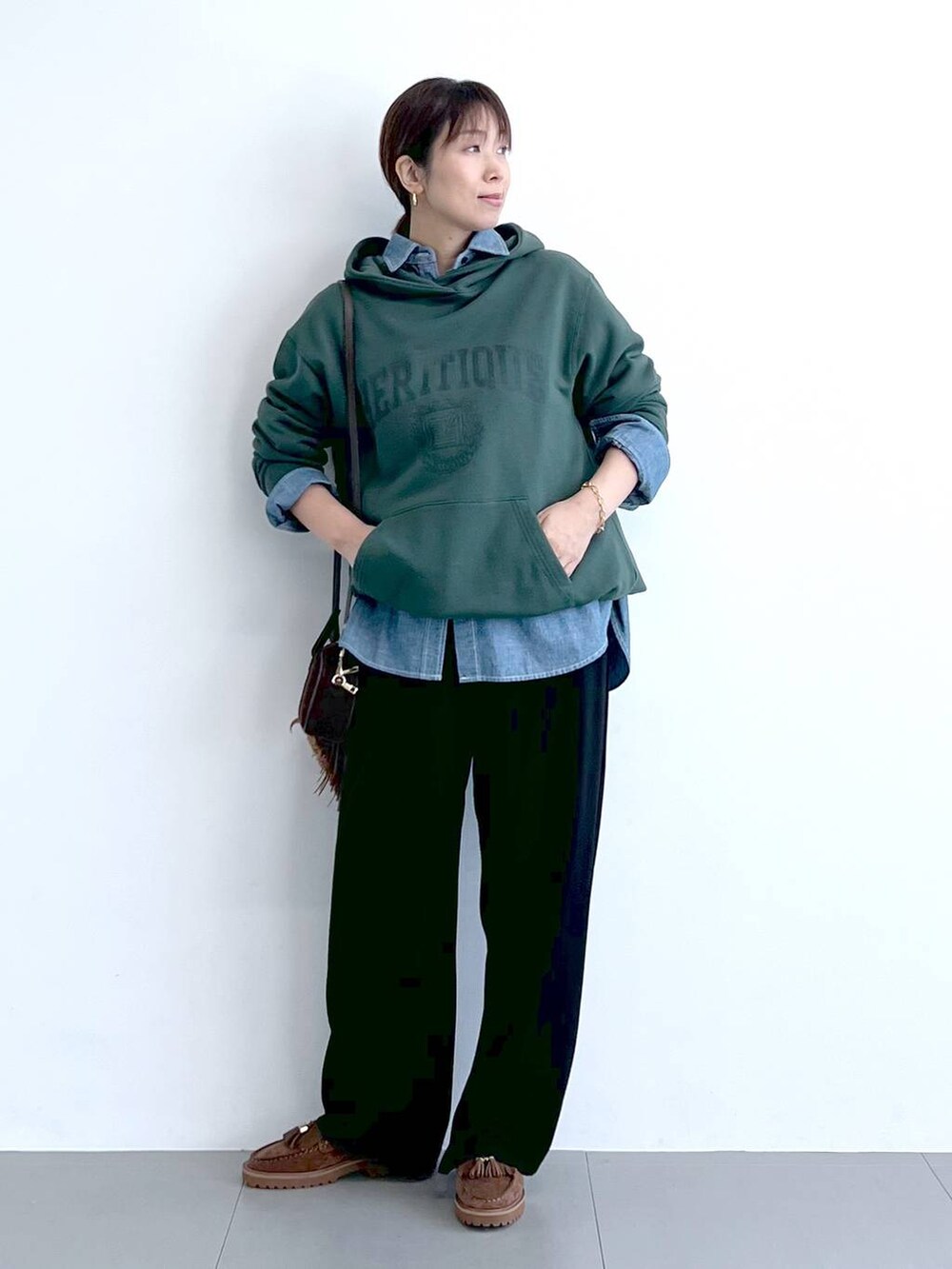 ブラック系のスラックス、グリーン系のパーカー、ブラウン系のショルダーバッグを着用したレディースの秋コーディネートの4枚目の写真