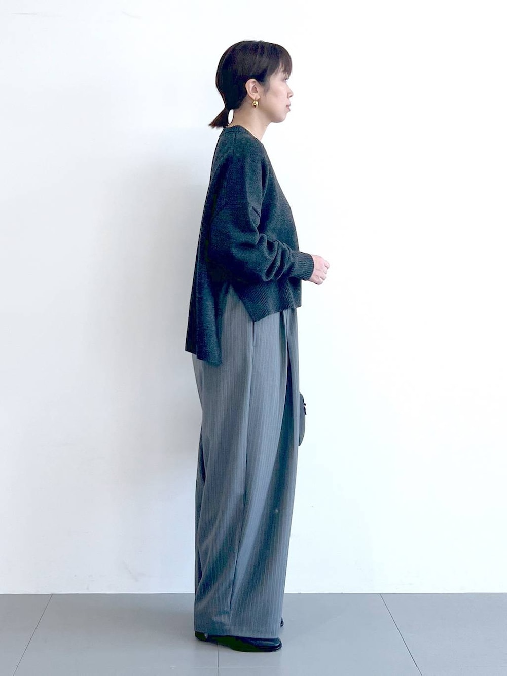 ブラック系のボストンバッグ、ブラック系のブーツ、グレー系のニット/セーターを着用したレディースの秋コーディネートの7枚目の写真