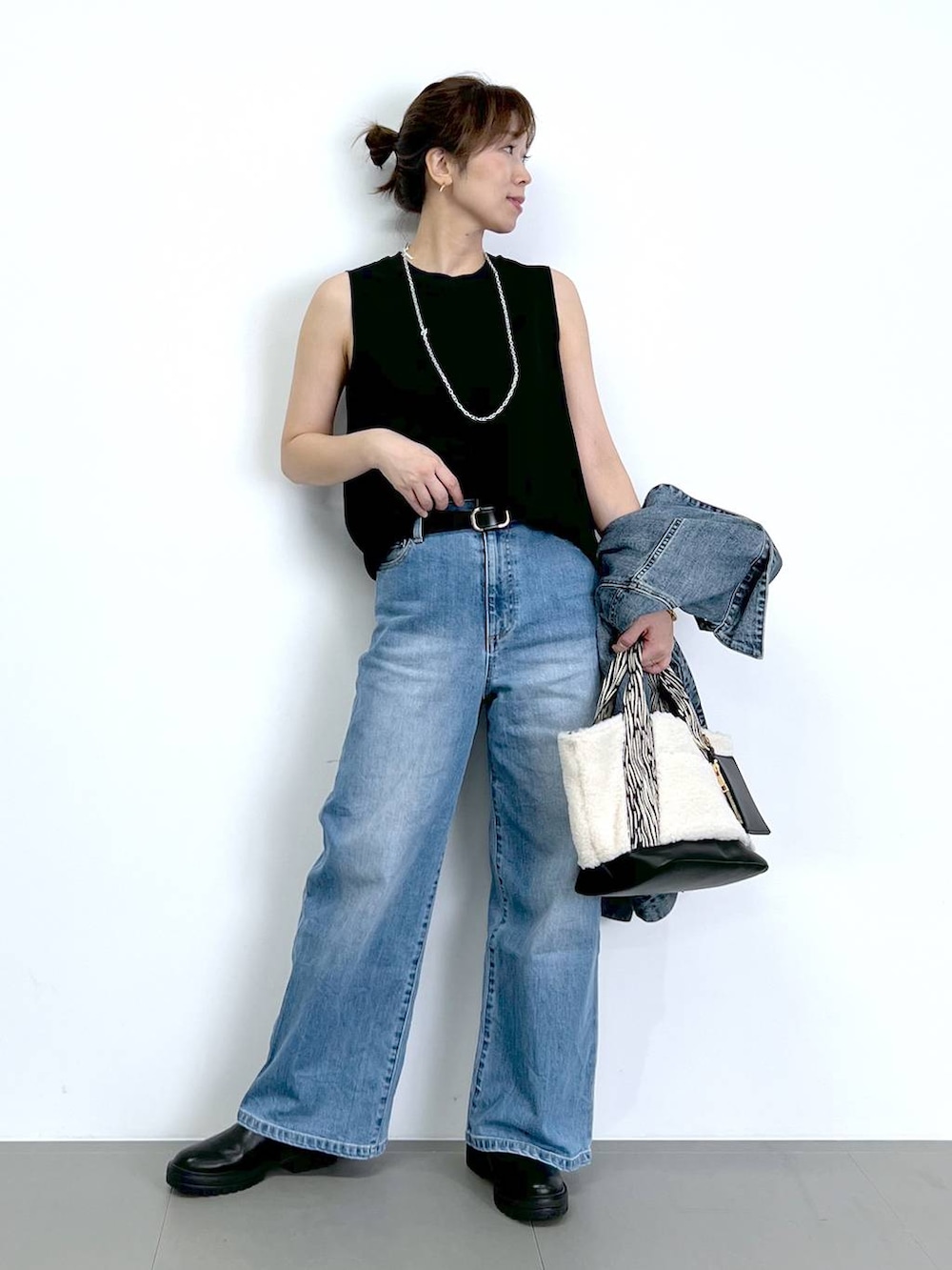 ブルー系のデニムパンツ、ブラック系のTシャツ/カットソー、ブラック系のブーツを着用したレディースの秋コーディネートの7枚目の写真