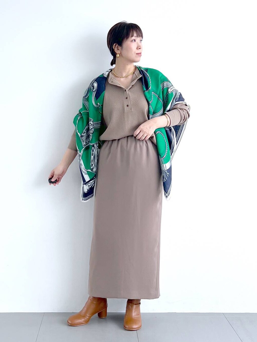 ブラウン系のスカート、イエロー系のブーツ、その他のトートバッグを着用したレディースの秋コーディネートの2枚目の写真