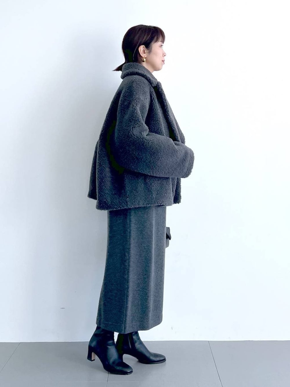 グレー系のピーコート、ブラック系のハンドバッグ、ブラック系のブーツを着用したレディースの秋コーディネートの5枚目の写真