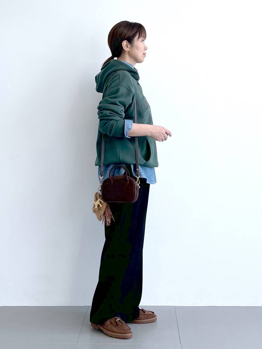 ブラック系のスラックス、グリーン系のパーカー、ブラウン系のショルダーバッグを着用したレディースの秋コーディネートの8枚目の写真