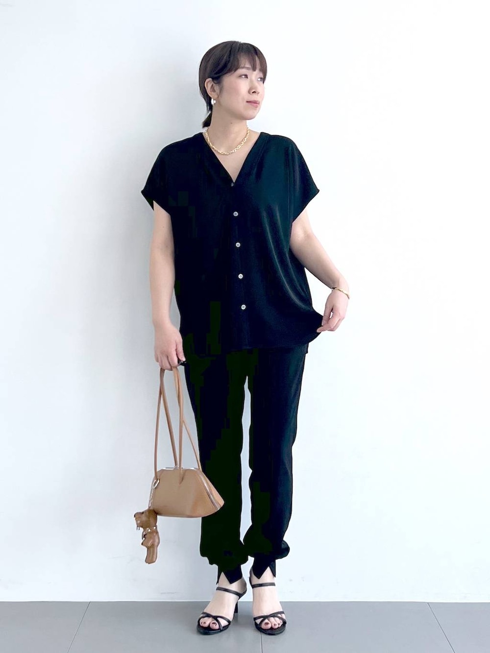 ブラウン系のハンドバッグ、ブラック系のシャツ/ブラウス、ブラック系のサンダルを着用したレディースの春コーディネートの5枚目の写真