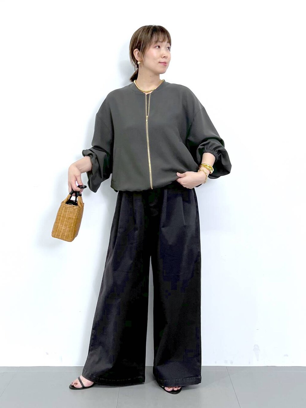 グレー系のブルゾン、ブラック系のショルダーバッグ、ブラック系のサンダルを着用したレディースの秋コーディネートの2枚目の写真